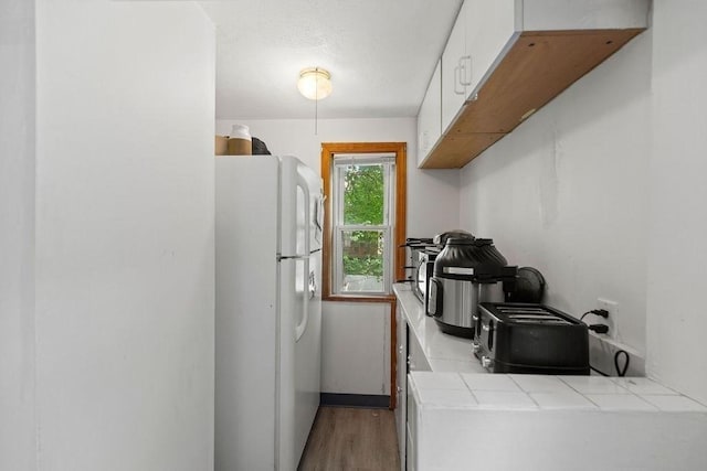 42 Carolina Ave, Boston, MA 02130 - kitchen with freestanding refrigerator, tile countertops, white cabinetry, and wood finished floors