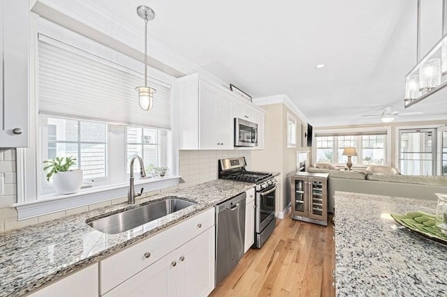 kitchen with hanging light fixtures, backsplash, white cabinetry, appliances with stainless steel finishes, and sink