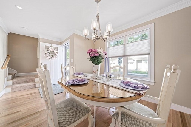 dining room featuring crown molding, light wood-type flooring, an inviting chandelier, and a wealth of natural light