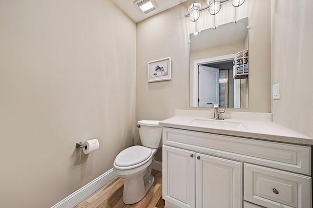 bathroom with toilet, vanity, and hardwood / wood-style flooring