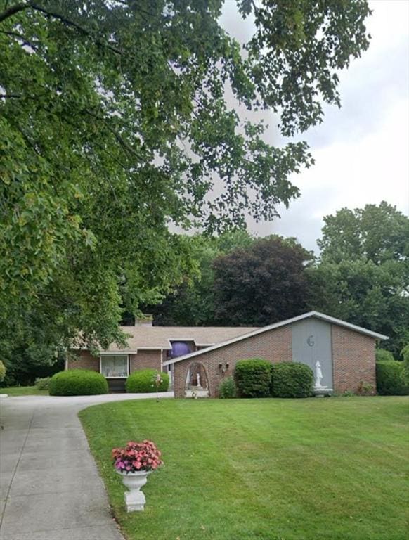 view of front of home featuring driveway, a front lawn, and brick siding