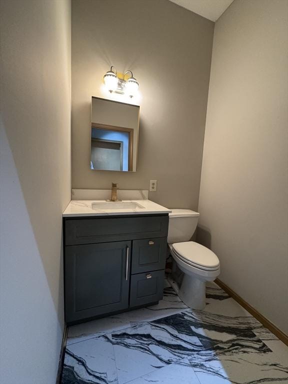 half bath with marble finish floor, toilet, vanity, and baseboards