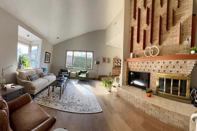 living area with a wealth of natural light, a fireplace, high vaulted ceiling, and wood finished floors