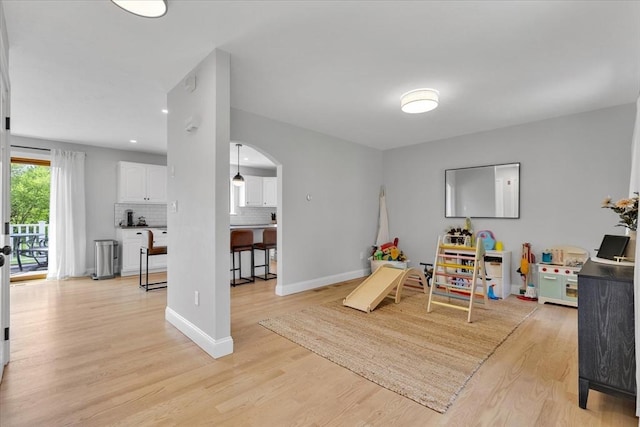 rec room with arched walkways, light wood-style flooring, baseboards, and recessed lighting