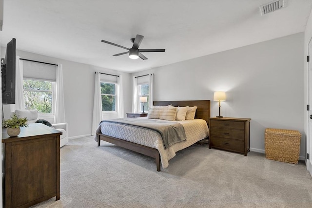 bedroom featuring multiple windows, light carpet, baseboards, and a ceiling fan