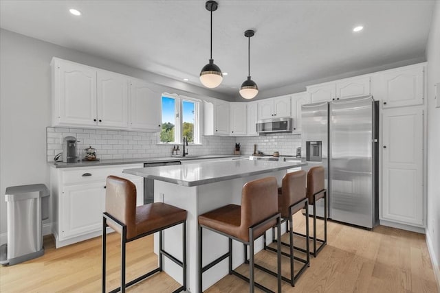 kitchen featuring appliances with stainless steel finishes, a breakfast bar, light wood-type flooring, decorative backsplash, and recessed lighting
