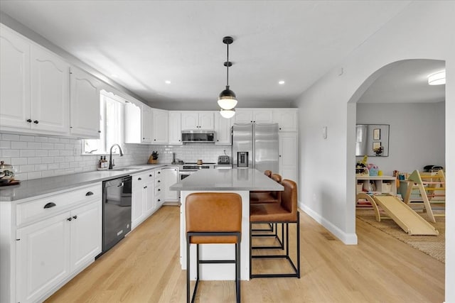 kitchen featuring appliances with stainless steel finishes, light wood-style flooring, a sink, a breakfast bar area, and recessed lighting