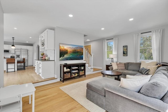 living room with recessed lighting, light wood finished floors, and stairs