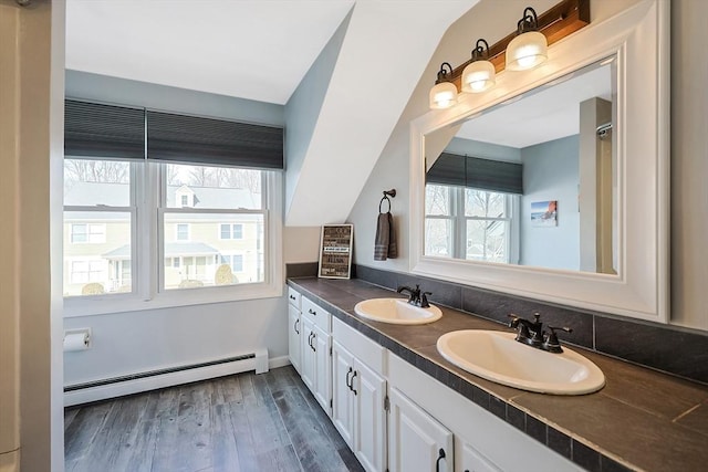 bathroom with a baseboard heating unit, double vanity, a sink, and wood finished floors