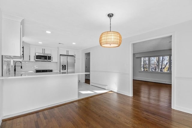 kitchen with hanging light fixtures, stainless steel appliances, backsplash, dark hardwood / wood-style flooring, and white cabinetry