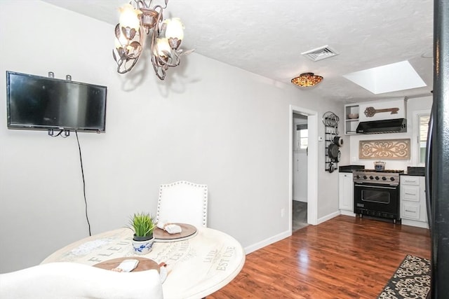 dining room featuring a notable chandelier, a skylight, visible vents, baseboards, and dark wood finished floors