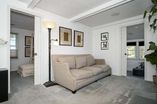 living area featuring baseboards, beam ceiling, and light colored carpet