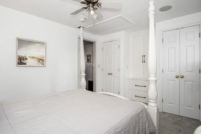 bedroom featuring light carpet, attic access, a ceiling fan, and multiple closets