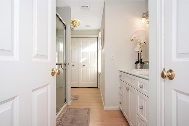 bathroom with visible vents, a stall shower, vanity, wood finished floors, and baseboards