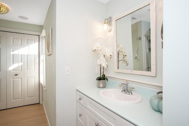 bathroom with a closet, vanity, and wood finished floors