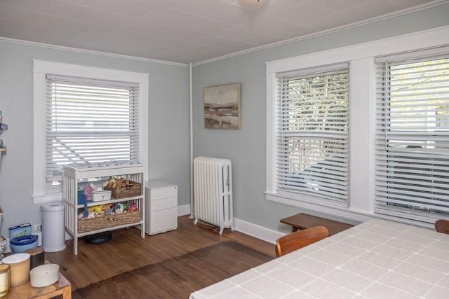 bedroom with radiator, ornamental molding, baseboards, and wood finished floors