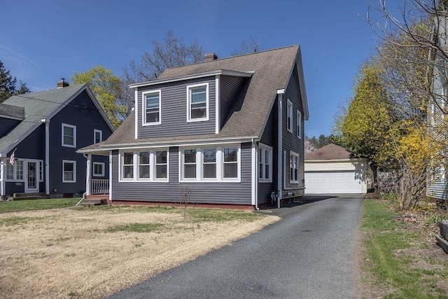 view of front of home featuring a detached garage, an outbuilding, a chimney, and a shingled roof