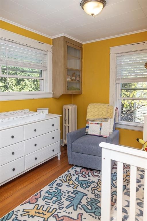 bedroom featuring radiator, ornamental molding, and wood finished floors