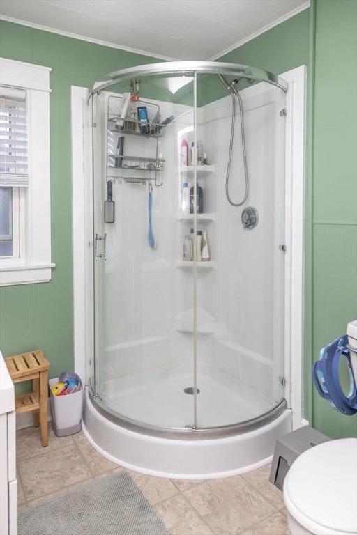 bathroom featuring ornamental molding, a stall shower, and toilet