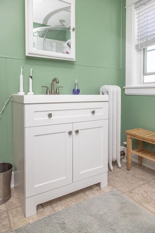 bathroom with vanity, a decorative wall, and radiator heating unit