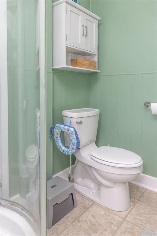 bathroom featuring tile patterned flooring, a decorative wall, and toilet