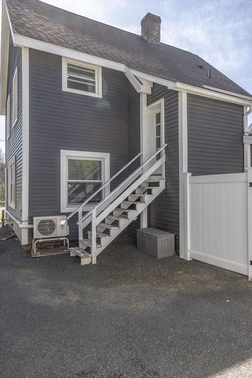 rear view of property with fence, ac unit, stairs, and a chimney
