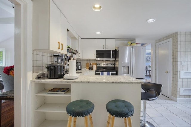 298 Oakland Rd, Barnstable, MA 02601 - kitchen featuring appliances with stainless steel finishes, a peninsula, a breakfast bar, tasteful backsplash, and white cabinets