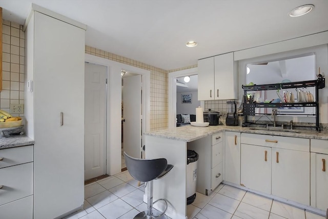 298 Oakland Rd, Barnstable, MA 02601 - kitchen with a sink, white cabinets, light stone counters, light tile patterned flooring, and recessed lighting