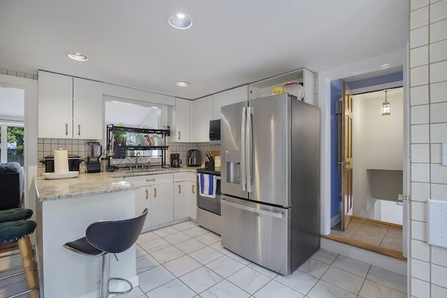 298 Oakland Rd, Barnstable, MA 02601 - kitchen with stainless steel fridge with ice dispenser, electric range, a peninsula, white cabinetry, and tasteful backsplash