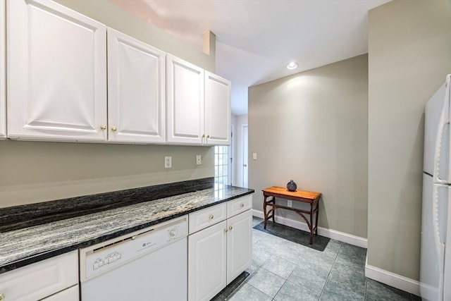 kitchen featuring dark stone countertops, light tile patterned floors, white cabinets, and white appliances