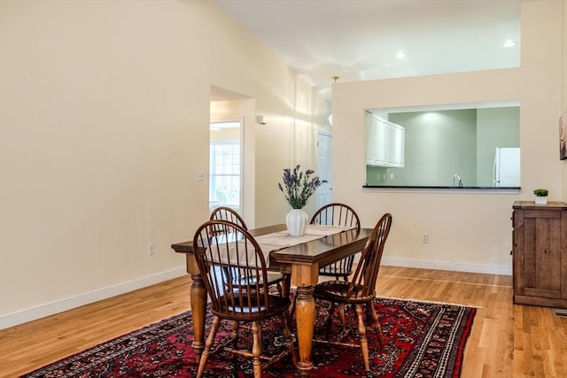 dining area featuring lofted ceiling and light wood-type flooring