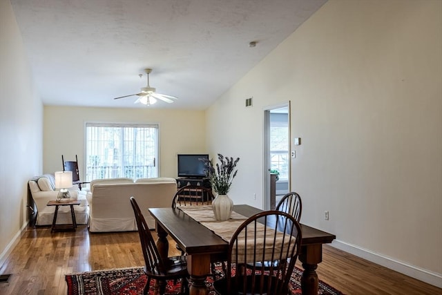 dining area featuring ceiling fan, wood-type flooring, and vaulted ceiling