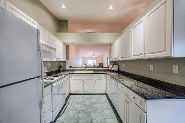 kitchen with sink, white cabinets, dark stone counters, and white appliances