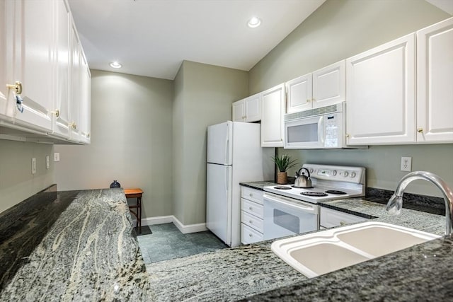 kitchen featuring white appliances, white cabinetry, dark stone counters, and sink