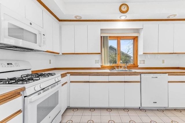 kitchen with a sink, light countertops, white cabinets, and white appliances