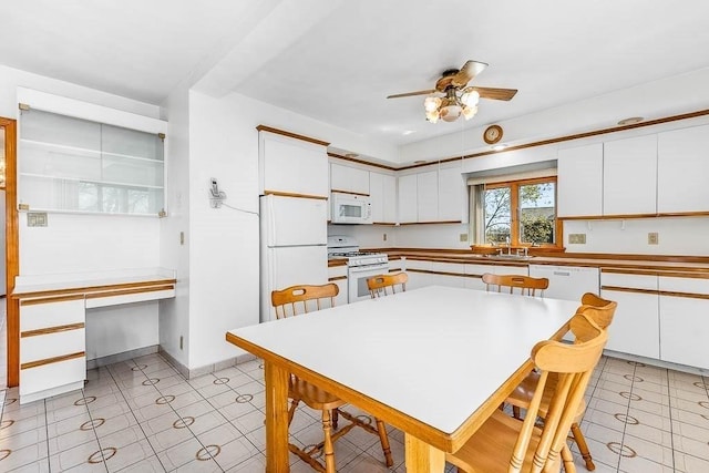 kitchen featuring a ceiling fan, built in study area, baseboards, white appliances, and white cabinetry
