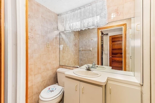 bathroom with toilet, tile walls, and vanity