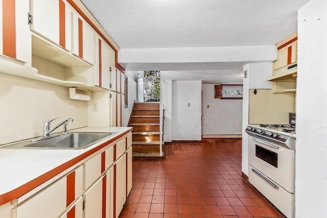 kitchen featuring a sink, light countertops, a textured ceiling, under cabinet range hood, and white range with gas cooktop