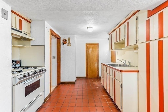 kitchen featuring white gas stove, a textured ceiling, a sink, light countertops, and under cabinet range hood