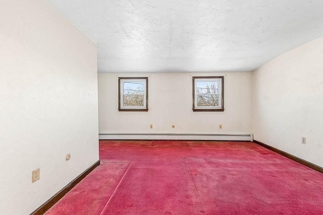 carpeted spare room with baseboards, a baseboard heating unit, and a textured ceiling
