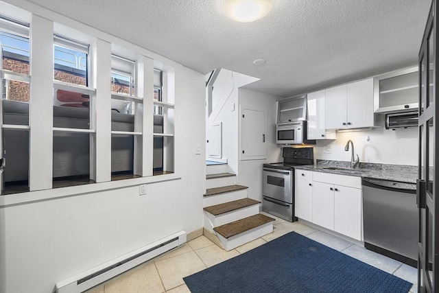 kitchen with appliances with stainless steel finishes, white cabinetry, a baseboard radiator, sink, and light tile patterned floors