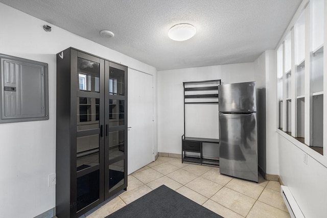 kitchen with a baseboard radiator, light tile patterned floors, stainless steel refrigerator, and french doors