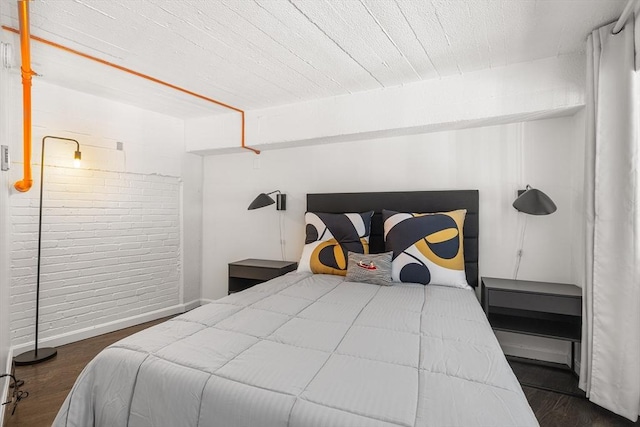 bedroom featuring brick wall and dark hardwood / wood-style floors