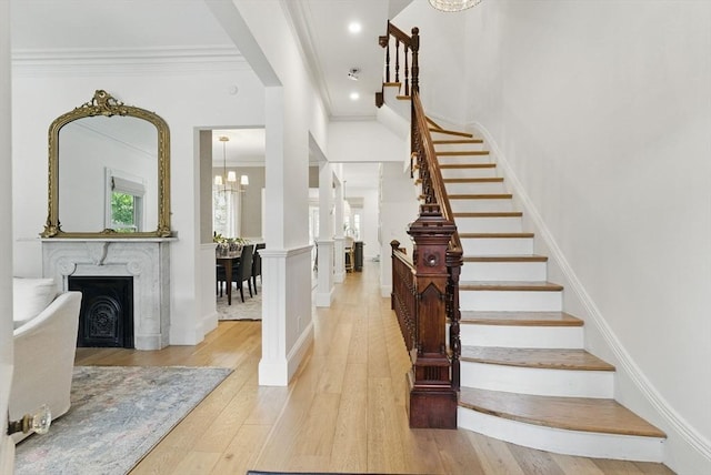 782 E 4th St, Boston, MA 02127 - foyer entrance featuring a chandelier, ornamental molding, light wood-style flooring, a fireplace, and stairs