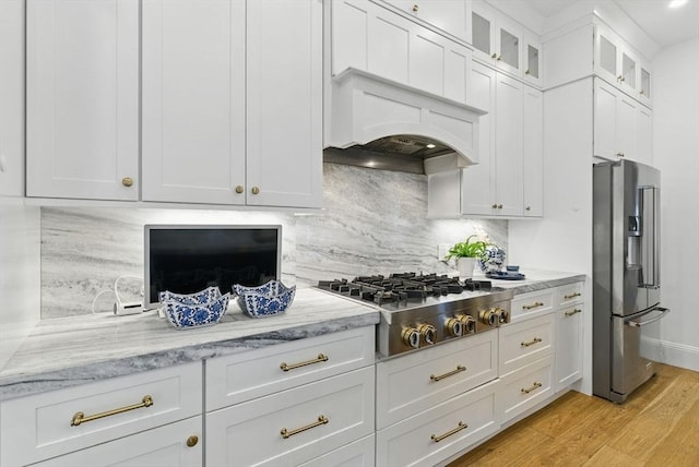 782 E 4th St, Boston, MA 02127 - kitchen with appliances with stainless steel finishes, tasteful backsplash, light stone countertops, light wood-type flooring, and white cabinetry