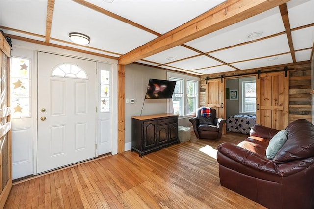 entryway featuring a barn door, beam ceiling, and light hardwood / wood-style flooring