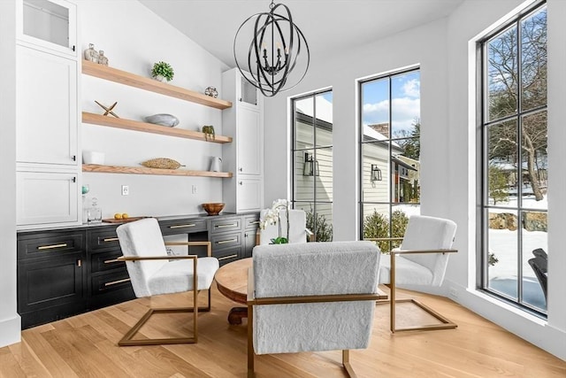 living area with a notable chandelier, built in desk, and light hardwood / wood-style floors