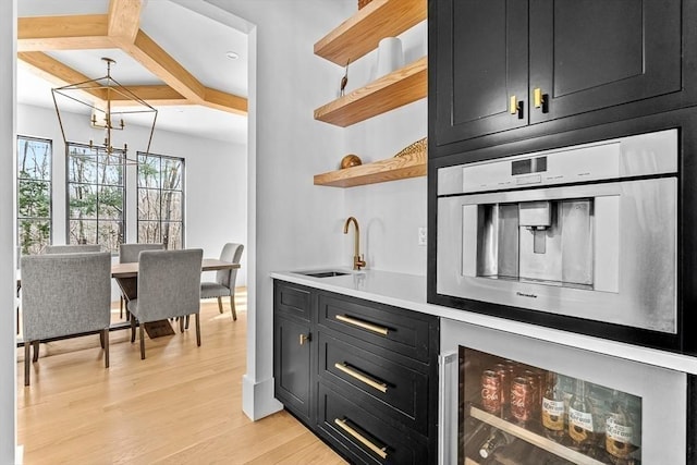 bar featuring wine cooler, coffered ceiling, sink, decorative light fixtures, and light hardwood / wood-style flooring