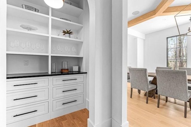 bar with an inviting chandelier, built in shelves, light hardwood / wood-style floors, and white cabinets