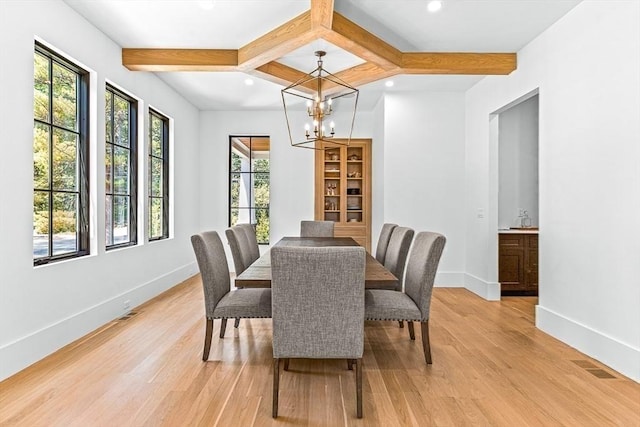 dining area with coffered ceiling, beam ceiling, an inviting chandelier, and light wood-type flooring